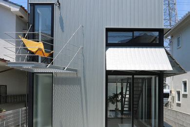 Ejemplo de fachada de casa moderna pequeña de dos plantas con tejado plano y tejado de metal