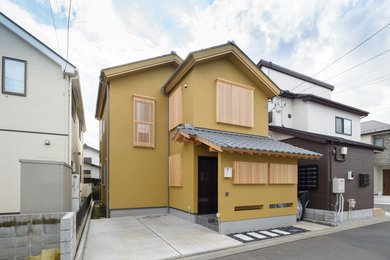 Diseño de fachada de casa beige asiática pequeña de dos plantas con tejado a dos aguas y tejado de teja de barro