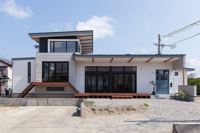 Modelo de fachada de casa blanca costera de tamaño medio a niveles con revestimiento de metal, tejado de un solo tendido y tejado de metal