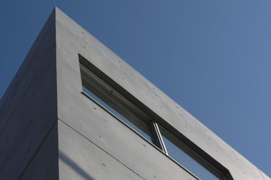 Ejemplo de fachada de piso gris industrial de tres plantas con tejado plano
