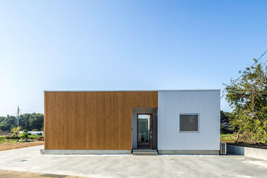 Modelo de fachada de casa marrón de estilo zen de tamaño medio de una planta con revestimientos combinados, tejado de un solo tendido y tejado de metal