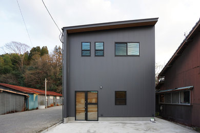 Imagen de fachada de casa negra industrial de dos plantas con revestimiento de metal, tejado de un solo tendido y tejado de metal