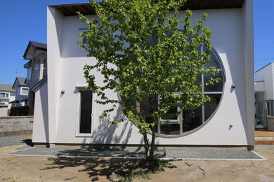 Foto på ett mellanstort funkis vitt hus, med två våningar, metallfasad, pulpettak och tak i metall