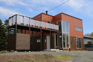Cette image montre une petite façade de maison marron chalet à un étage avec un toit plat et un toit en métal.