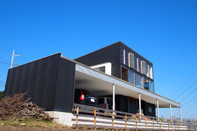 Foto de fachada negra minimalista de dos plantas con revestimiento de metal y tejado de un solo tendido