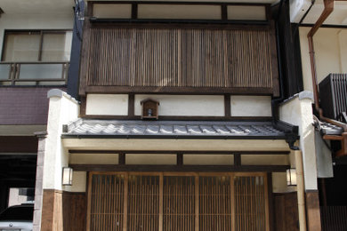 Ejemplo de fachada de casa marrón minimalista pequeña a niveles con revestimiento de estuco, tejado a dos aguas y tejado de teja de barro