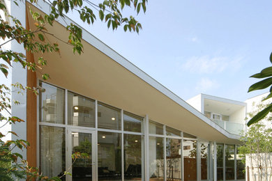 Imagen de fachada de casa blanca moderna grande de dos plantas con revestimiento de aglomerado de cemento, tejado de un solo tendido y tejado de metal