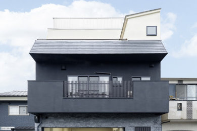 Ejemplo de fachada de casa negra de tres plantas con revestimiento de adobe