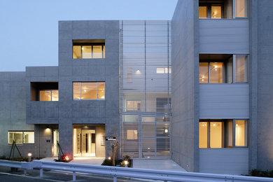 Modelo de fachada gris actual de tres plantas con revestimiento de hormigón y tejado plano