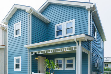На фото: двухэтажный, синий частный загородный дом в морском стиле с комбинированной облицовкой, полувальмовой крышей и металлической крышей