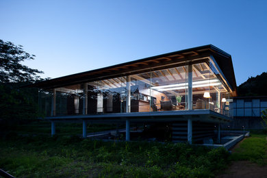Ejemplo de fachada de casa industrial de una planta con revestimiento de vidrio y tejado a dos aguas