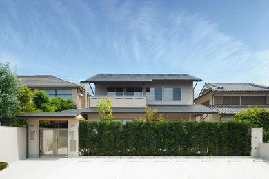 Ejemplo de fachada de casa gris asiática grande de dos plantas con tejado a dos aguas y tejado de metal