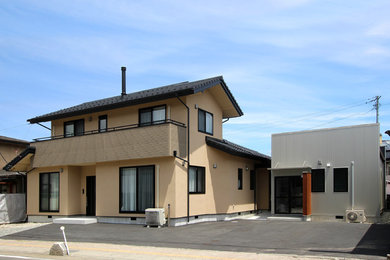 Esempio della villa grande beige moderna a due piani con tetto a capanna e copertura in tegole