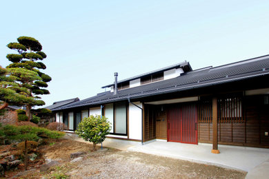 Imagen de fachada de casa marrón asiática grande de una planta con revestimiento de madera, tejado a dos aguas y tejado de teja de barro