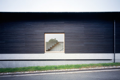 Immagine della villa nera moderna a tre piani con rivestimento in legno, tetto a capanna e copertura in metallo o lamiera