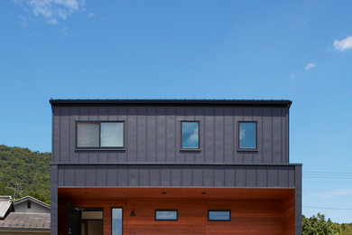 Diseño de fachada negra actual de dos plantas con revestimiento de madera y tejado plano