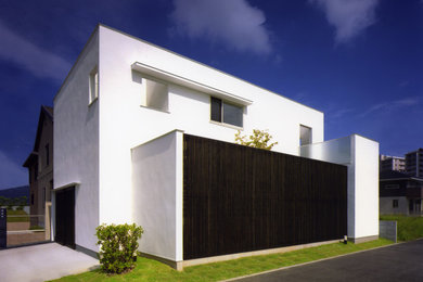 Ejemplo de fachada de casa minimalista de tamaño medio de dos plantas con revestimiento de estuco y tejado plano