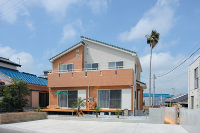 Cette image montre une façade de maison multicolore marine de taille moyenne et à un étage avec un revêtement mixte, un toit à deux pans et un toit en tuile.