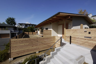 Medium sized and white world-inspired bungalow render detached house in Osaka with a pitched roof and a metal roof.