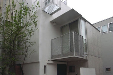 Diseño de fachada de casa blanca urbana pequeña de tres plantas con revestimiento de hormigón y tejado plano