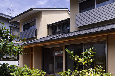 Ejemplo de fachada beige moderna de dos plantas con revestimiento de adobe