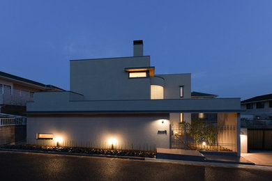 Idée de décoration pour une grande façade de maison grise minimaliste en stuc à un étage avec un toit plat et un toit mixte.