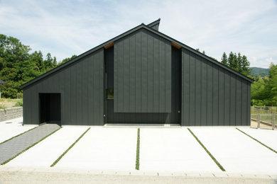 Diseño de fachada de casa negra moderna de tamaño medio de dos plantas con revestimiento de metal, tejado a dos aguas y tejado de metal