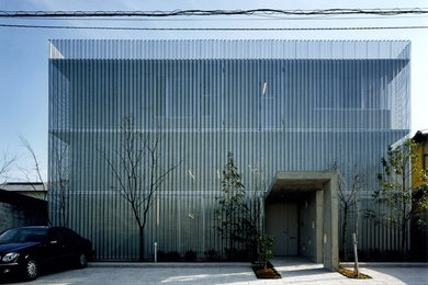 Diseño de fachada de casa gris moderna de tres plantas con revestimiento de metal y tejado plano