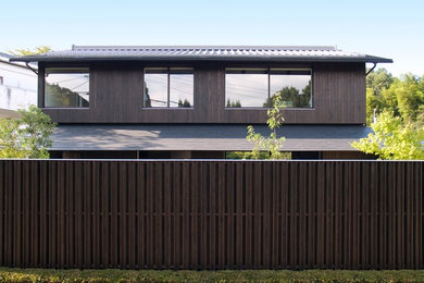 Ejemplo de fachada de casa marrón asiática de dos plantas con revestimiento de madera, tejado a dos aguas y tejado de varios materiales