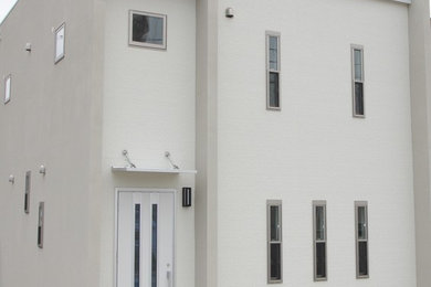 Ejemplo de fachada de casa blanca minimalista de dos plantas con revestimientos combinados, tejado plano y tejado de metal