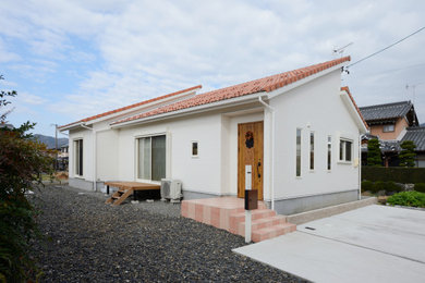 Modelo de fachada de casa blanca mediterránea de tamaño medio de una planta con revestimientos combinados, tejado a la holandesa y tejado de teja de barro