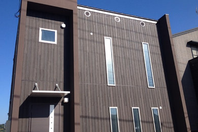Foto de fachada de casa marrón moderna con revestimientos combinados, tejado plano y tejado de metal