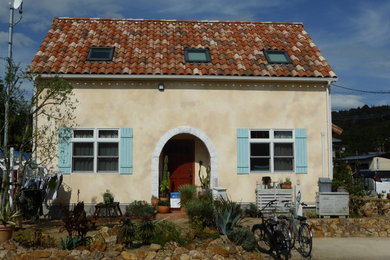 Ejemplo de fachada de casa amarilla mediterránea de tamaño medio de dos plantas con revestimiento de estuco, tejado a dos aguas y tejado de teja de barro