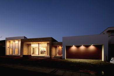 Modelo de fachada de casa beige moderna grande de una planta con revestimiento de hormigón, tejado plano y tejado de metal