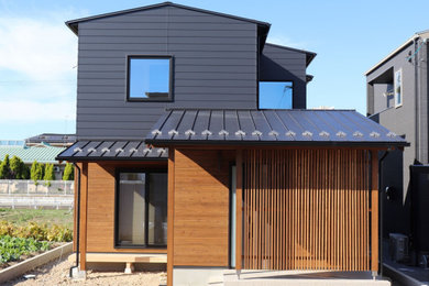 Imagen de fachada de casa negra asiática de dos plantas con revestimiento de metal, tejado a dos aguas y tejado de metal