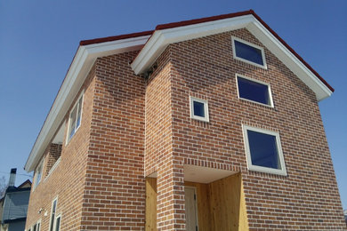 Modelo de fachada de casa marrón de tamaño medio de dos plantas con revestimiento de ladrillo, tejado a dos aguas y tejado de metal
