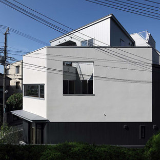 Modelo de fachada blanca, moderna, pequeña, de tres plantas, con revestimiento de estuco, tejado a doble faldón y tejado de metal