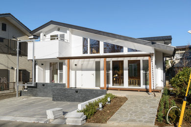 Imagen de fachada blanca contemporánea grande de dos plantas con revestimiento de estuco y tejado a dos aguas