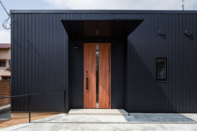 Imagen de fachada de casa negra minimalista de una planta con revestimiento de metal, tejado de un solo tendido y tejado de metal