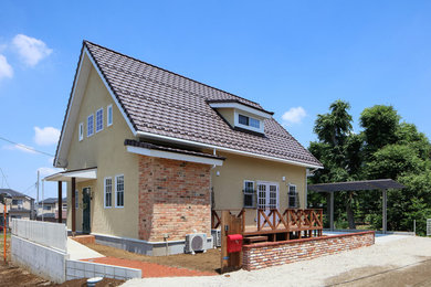 На фото: двухэтажный, желтый частный загородный дом в стиле шебби-шик с двускатной крышей и черепичной крышей с