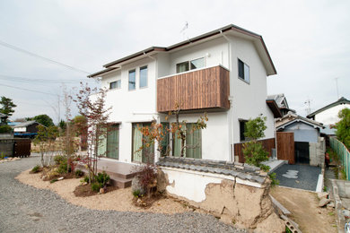Ejemplo de fachada de casa blanca de estilo zen de tamaño medio de dos plantas con revestimiento de estuco, tejado a dos aguas y tejado de metal