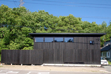 Imagen de fachada de casa negra minimalista pequeña de dos plantas con revestimiento de madera, tejado plano y tejado de metal