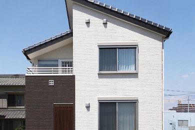 Imagen de fachada blanca contemporánea de dos plantas con revestimiento de aglomerado de cemento y tejado a dos aguas