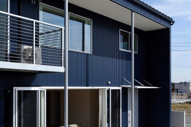 Imagen de fachada de casa azul de dos plantas con tejado de un solo tendido y tejado de metal