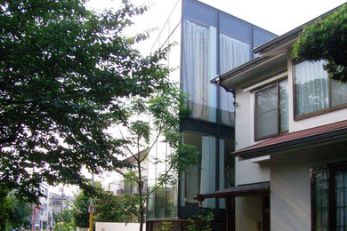 Ejemplo de fachada de casa blanca moderna a niveles con revestimiento de vidrio y tejado plano