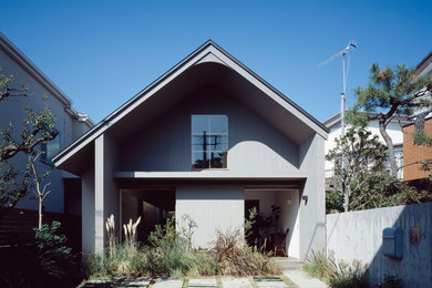 Cette image montre une façade de maison grise minimaliste en bois à un étage avec un toit à deux pans et un toit en métal.