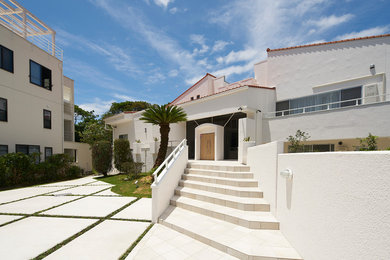 Diseño de fachada de piso blanca costera a niveles con tejado de un solo tendido y tejado de teja de barro