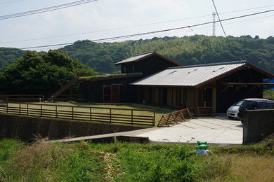 Diseño de fachada negra de estilo zen de dos plantas con revestimiento de madera y tejado a dos aguas