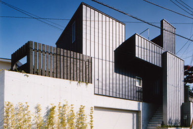 Diseño de fachada de casa negra minimalista de tamaño medio de tres plantas con revestimiento de metal, tejado de un solo tendido y tejado de metal