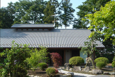 Diseño de fachada de casa beige asiática de tamaño medio de dos plantas con tejado a la holandesa y tejado de teja de barro